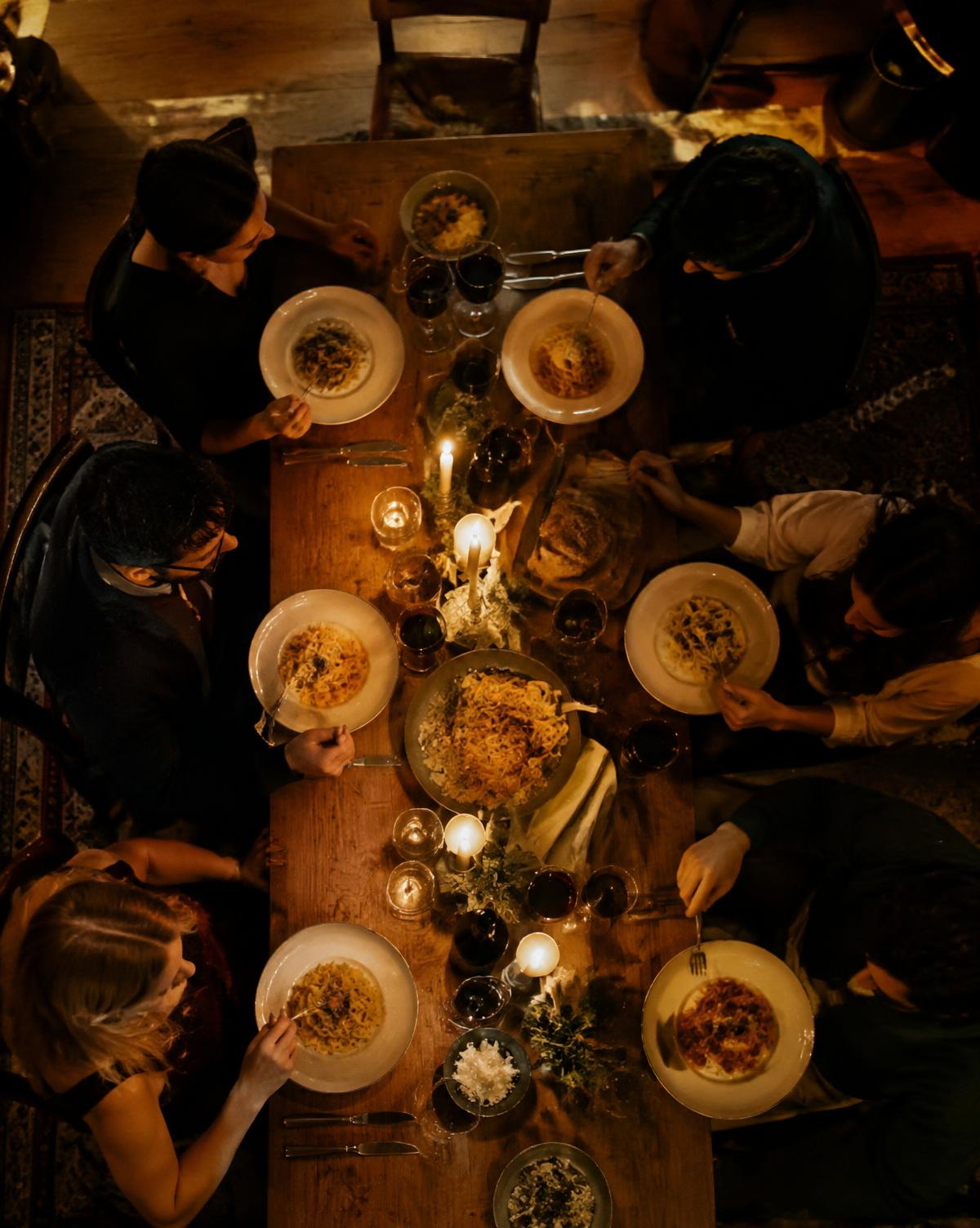 Candlelit long table with pasta and wine