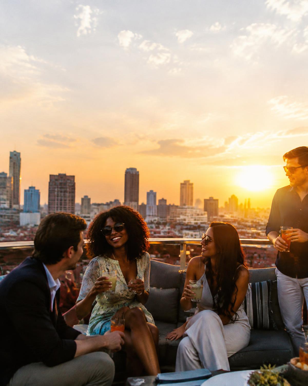Colleagues with cocktails on a rooftop at golden hour